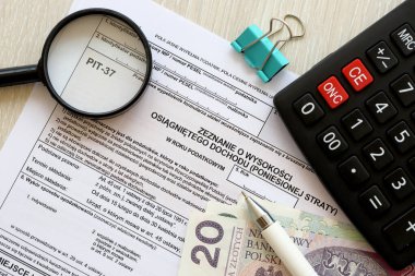 Kazanılan gelir ya da zarar miktarının beyanı, muhasebeci masasının üzerindeki PIT-37 vergi formları ve kalem ve zloti para faturalarının kapatılması