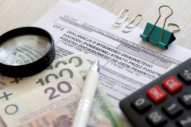 Kurumsal gelir vergisi mükellefleri tarafından kazanılan gelir miktarı veya zarar beyanı, muhasebeci masasının üzerindeki CIT-2 vergi formları, kalem ve cilalı zloti para faturaları kapanıyor