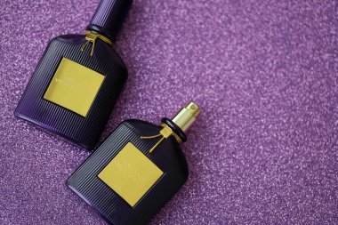 KYIV, UKRAINE - 27 Kasım 2023 Tom Ford kadife orkide parfüm şişesi açık leylak arka planda yatar. Tom Ford, Amerikalı moda tasarımcısı. 2006 'da ünlü lüks markasını kurdu.