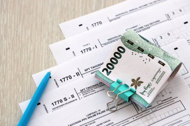 Kalem ve Endonezya rupia banknotlarıyla yıllık gelir vergisi iade formları. Asıl adı Surat Pemberitahuan Pajak veya SPT Tahunan.