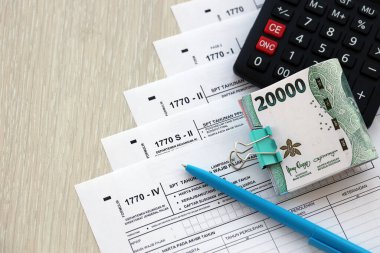 Kalem ve Endonezya rupia banknotlarıyla yıllık gelir vergisi iade formları. Asıl adı Surat Pemberitahuan Pajak veya SPT Tahunan.