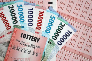 Kırmızı piyango bileti, Endonezya rupia parasıyla birlikte pembe kumar çarşaflarında yatıyor. Endonezya 'da piyango oynamak ya da kumar bağımlılığı