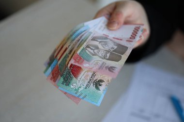 Kadın muhasebeci, bir sürü Endonezya rupia parası veriyor.