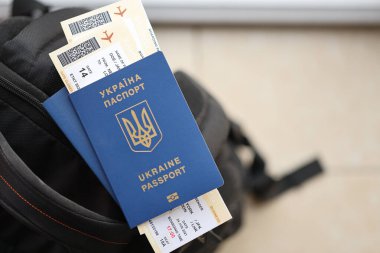 Siyah turistik sırt çantası üzerinde uçuş biletleri olan iki Ukrayna biyometrik pasaportu.