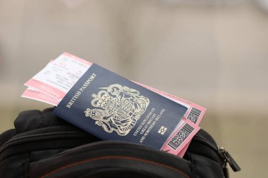 Turistik sırt çantasında uçak biletleri olan mavi İngiliz pasaportu. Turizm ve seyahat kavramı