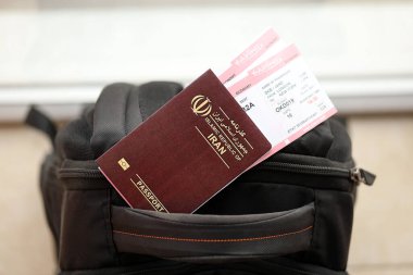 İran 'ın Kızıl İslam Cumhuriyeti pasaportu ve turistik sırt çantasında uçak biletleri. Turizm ve seyahat kavramı