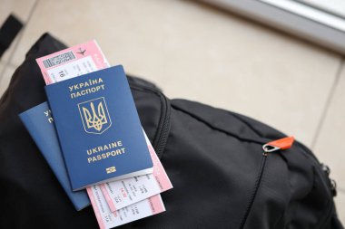 Siyah turistik sırt çantası üzerinde uçuş biletleri olan iki Ukrayna biyometrik pasaportu.