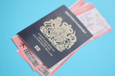 Mavi arka planda uçak biletleri olan mavi İngiliz pasaportu. Turizm ve seyahat kavramı