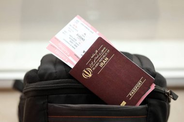 İran 'ın Kızıl İslam Cumhuriyeti pasaportu ve turistik sırt çantasında uçak biletleri. Turizm ve seyahat kavramı