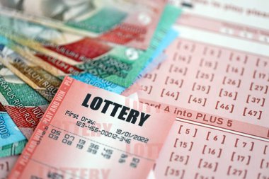 Kırmızı piyango bileti, Endonezya rupia parasıyla birlikte pembe kumar çarşaflarında yatıyor. Endonezya 'da piyango oynamak ya da kumar bağımlılığı