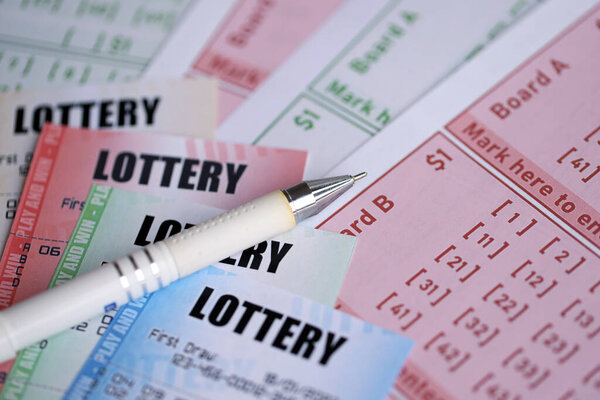 Лотерейные билеты разных цветов и ручка на пустых купюрах с номерами для игры в лотерею крупным планом