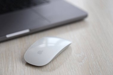 KYIV, UKRAINE - NOVEMBER 27, 2023 Apple Magic Mouse 3rd generation lies with grey MacBook 2021 close up clipart