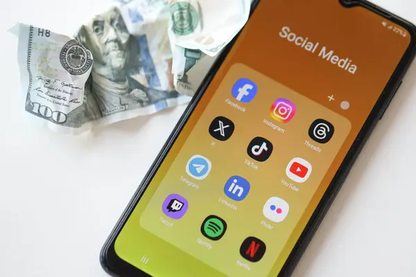 stock image KYIV, UKRAINE - FEBRUARY 28, 2024 Social Media on smartphone display and crumpled dollar bill as concept of spend money to social networks and media services