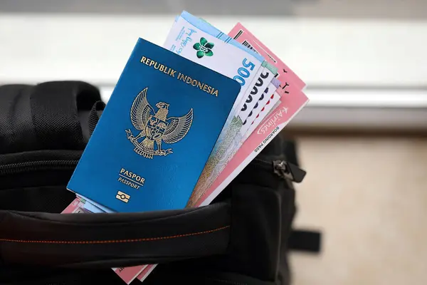 Blue Republic Indonesia passport with money and airline tickets on touristic backpack close up. Tourism and travel concept