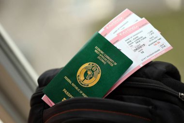 Turistik sırt çantası üzerinde uçak biletleri olan yeşil Nijerya pasaportu. Turizm ve seyahat kavramı