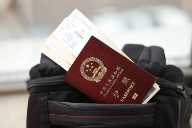 Çin Halk Cumhuriyeti 'nin kırmızı pasaportu ve sırt çantasında uçak biletleri var. PRC pasaportu