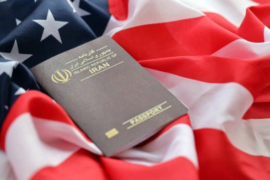 Red Islamic Republic of Iran passport on United States national flag background close up. Tourism and diplomacy concept clipart