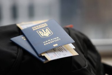 Siyah turistik sırt çantası üzerinde uçuş biletleri olan iki Ukrayna biyometrik pasaportu.