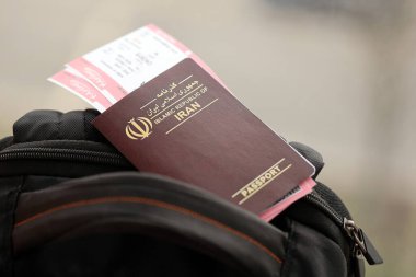 İran 'ın Kızıl İslam Cumhuriyeti pasaportu ve turistik sırt çantasında uçak biletleri. Turizm ve seyahat kavramı