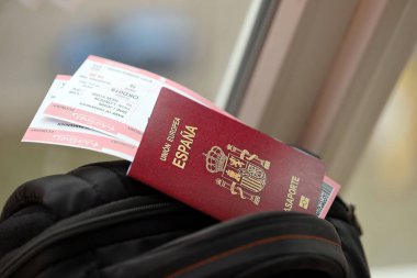 Red Spanish passport of European Union with airline tickets on touristic backpack close up. Tourism and travel concept clipart