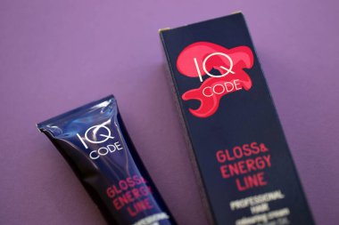 KYIV, UKRAINE - OCTOBER 31, 2023 Tube of IQ Code Gloss and Energy Line colorizer cream for hair close up clipart