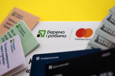 TERNOPİL, UKRAINE - 7 Temmuz 2023 Privatbank yeni bankacılık kartları ve masada para. Zarftaki yeni kart kapat