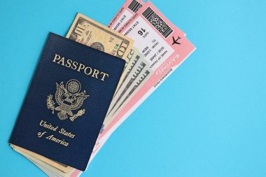 Blue United States of America passport with money and airline tickets on blue background close up. Tourism and travel concept clipart