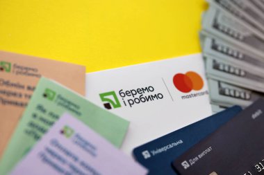 TERNOPİL, UKRAINE - 7 Temmuz 2023 Privatbank yeni bankacılık kartları ve masada para. Zarftaki yeni kart kapat