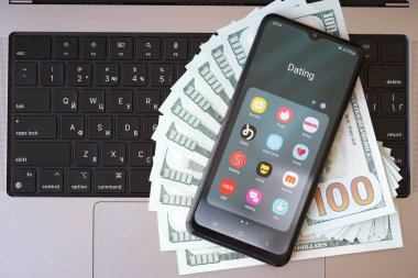 KYIV, UKRAINE - 28 Şubat 2024 MacBook klavyesinde akıllı telefon görüntüleme simgeleri ve Amerikan dolarları