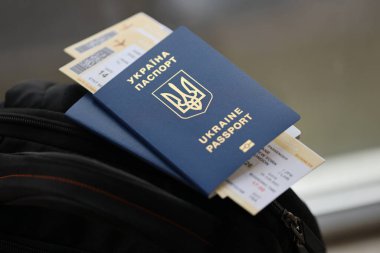 Siyah turistik sırt çantası üzerinde uçuş biletleri olan iki Ukrayna biyometrik pasaportu.