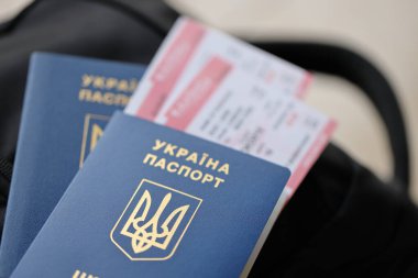 Siyah turistik sırt çantası üzerinde uçuş biletleri olan iki Ukrayna biyometrik pasaportu.