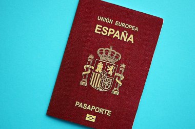 Red Spanish passport of European Union on blue background close up. Tourism and citizenship concept clipart
