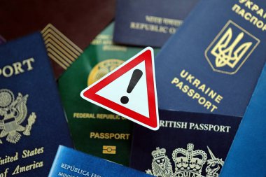 Farklı ülkelerin ve dünyanın farklı bölgelerinden birçok vatandaşın pasaportu ve uyarı levhası.