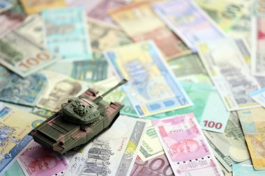 Farklı para birimlerinin banknotlarında küçük yeşil tank. Savaş finansmanı ya da savunma için para harcamak