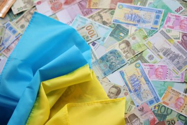 Farklı para birimlerinin banknotlarında Ukrayna bayrağı. Ukrayna 'daki savaş finansmanı ve askeri destek fiyatlarının geçmişi