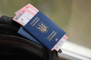 Siyah turistik sırt çantası üzerinde uçuş biletleri olan iki Ukrayna biyometrik pasaportu.
