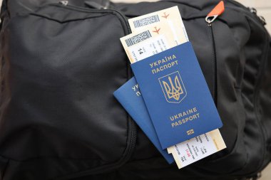 Siyah turistik sırt çantası üzerinde uçuş biletleri olan iki Ukrayna biyometrik pasaportu.