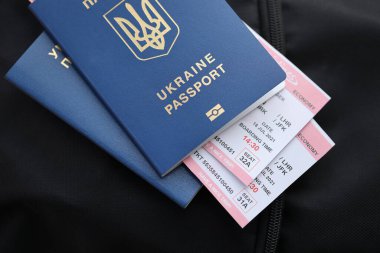 Siyah turistik sırt çantası üzerinde uçuş biletleri olan iki Ukrayna biyometrik pasaportu.