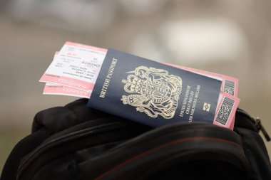 Turistik sırt çantasında uçak biletleri olan mavi İngiliz pasaportu. Turizm ve seyahat kavramı