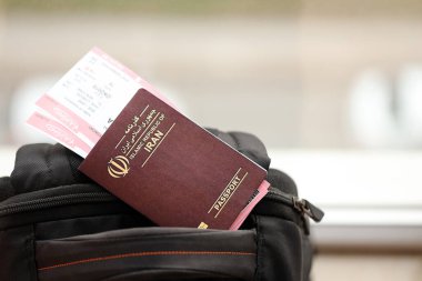 İran 'ın Kızıl İslam Cumhuriyeti pasaportu ve turistik sırt çantasında uçak biletleri. Turizm ve seyahat kavramı