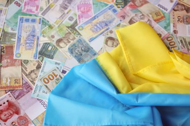 Farklı para birimlerinin banknotlarında Ukrayna bayrağı. Ukrayna 'daki savaş finansmanı ve askeri destek fiyatlarının geçmişi