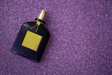 KYIV, UKRAINE - 27 Kasım 2023 Tom Ford kadife orkide parfüm şişesi açık leylak arka planda yatar. Tom Ford, Amerikalı moda tasarımcısı. 2006 'da ünlü lüks markasını kurdu.