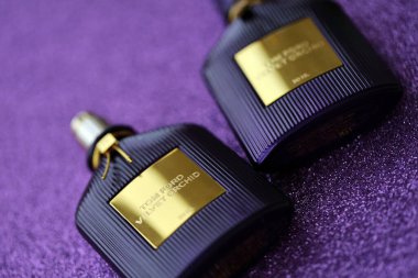 KYIV, UKRAINE - 27 Kasım 2023 Tom Ford kadife orkide parfüm şişesi açık leylak arka planda yatar. Tom Ford, Amerikalı moda tasarımcısı. 2006 'da ünlü lüks markasını kurdu.