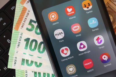 KYIV, UKRAINE - 28 Şubat 2024 MacBook klavyesinde ve avro banknotlarında akıllı telefon görüntülerinde flört uygulamaları simgeleri