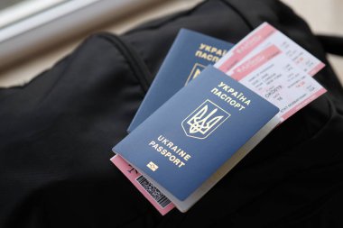 Siyah turistik sırt çantası üzerinde uçuş biletleri olan iki Ukrayna biyometrik pasaportu.