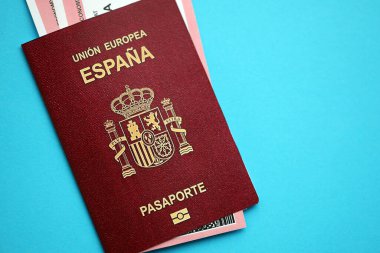 Red Spanish passport of European Union with airline tickets on blue background close up. Tourism and travel concept clipart