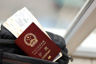 Çin Halk Cumhuriyeti 'nin kırmızı pasaportu ve sırt çantasında uçak biletleri var. PRC pasaportu