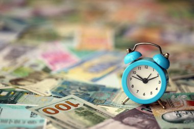 Farklı para birimlerinin banknotlarındaki küçük çalar saat. Zaman ve para arkaplanı kapat