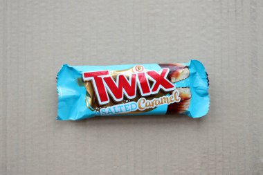 TERNOPİL, UKRAINE - 7 Temmuz 2023 Twix, ahşap zemin üzerinde tuzlu ve mavi karamel ambalajı. Twix, Mars Inc. 'in karamelli ve sütlü çikolatalı bisküvilerden oluşan bir çikolatadır.