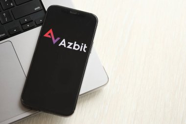 KYIV, UKRAINE - 15 Mart 2024 Azbit logosu MacBook panelinde iPhone ekranında. iPhone ekranında şifreli döviz portalı logosu ve MacBook 'ta dolar ve bitcoin var. Kripto para birimi